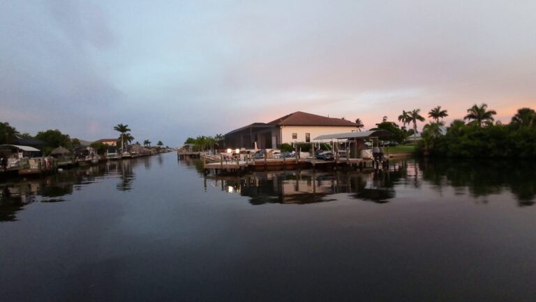 Lit waterfront home and dock on a Cape Coral canal at dusk