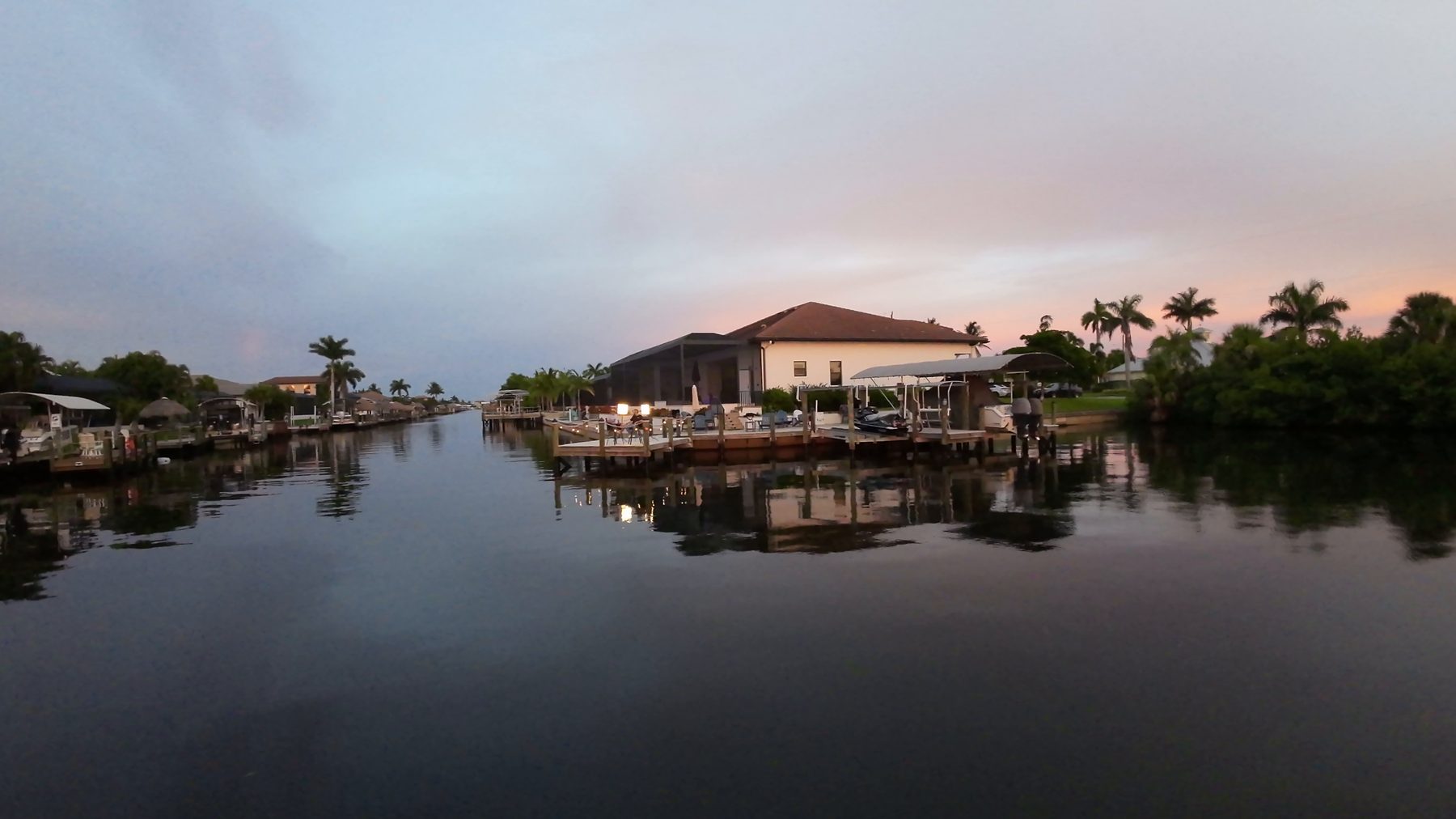 Lit waterfront home and dock on a Cape Coral canal at dusk