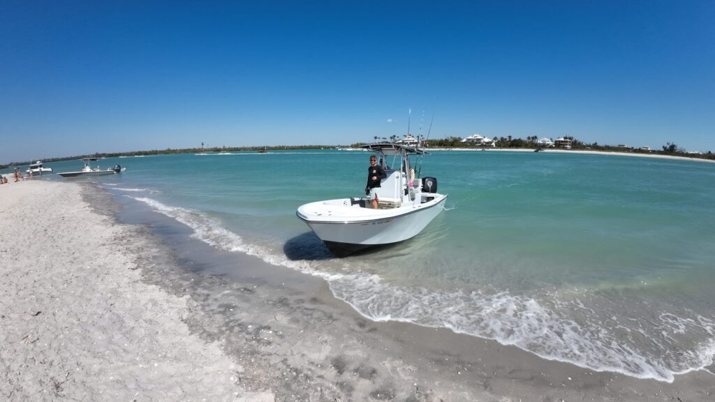 Center-console charter boat pulled up on a white sand beach