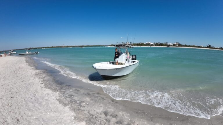Center-console charter boat pulled up on a white sand beach