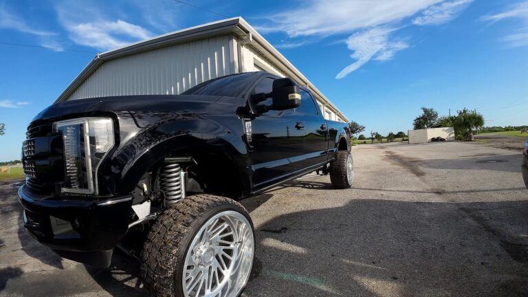 Lifted black pickup truck shot low by drone at a grand opening