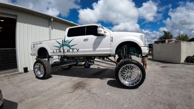 Lifted white truck on chrome wheels outside a shop