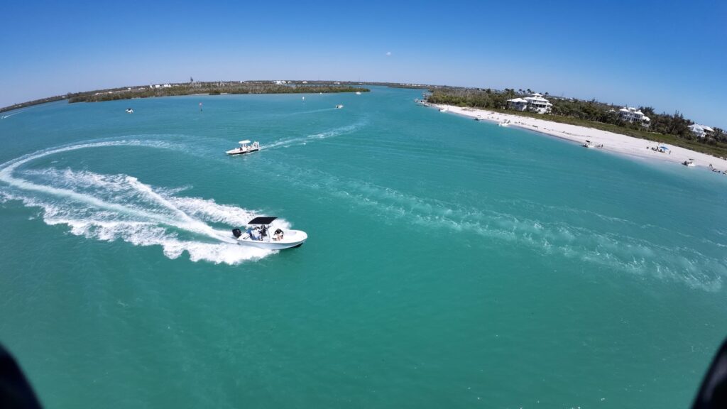Charter boat making a sweeping turn near a barrier island, FPV drone shot